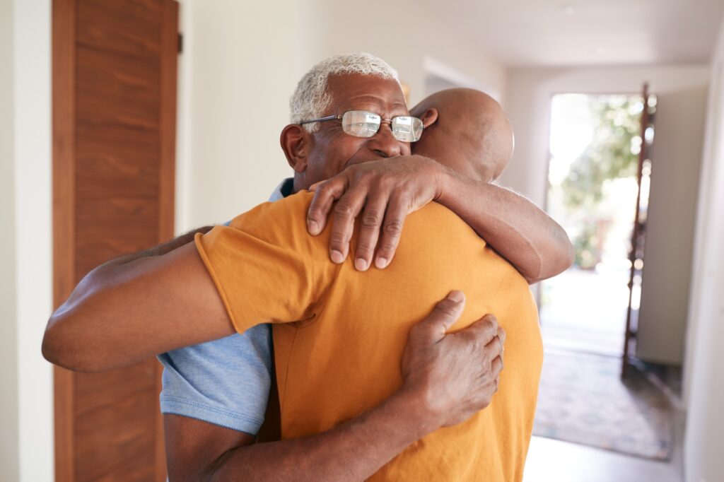 Loving Senior Father Hugging Adult Son Indoors At Home