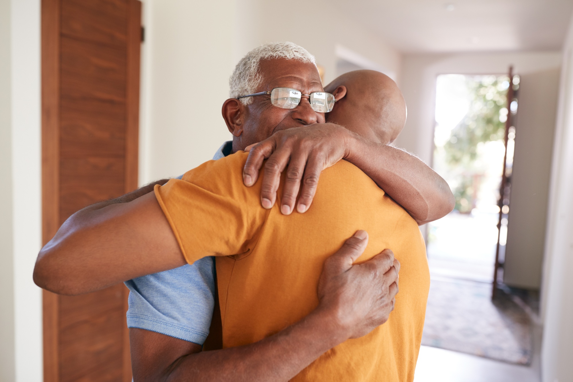 Loving Senior Father Hugging Adult Son Indoors At Home